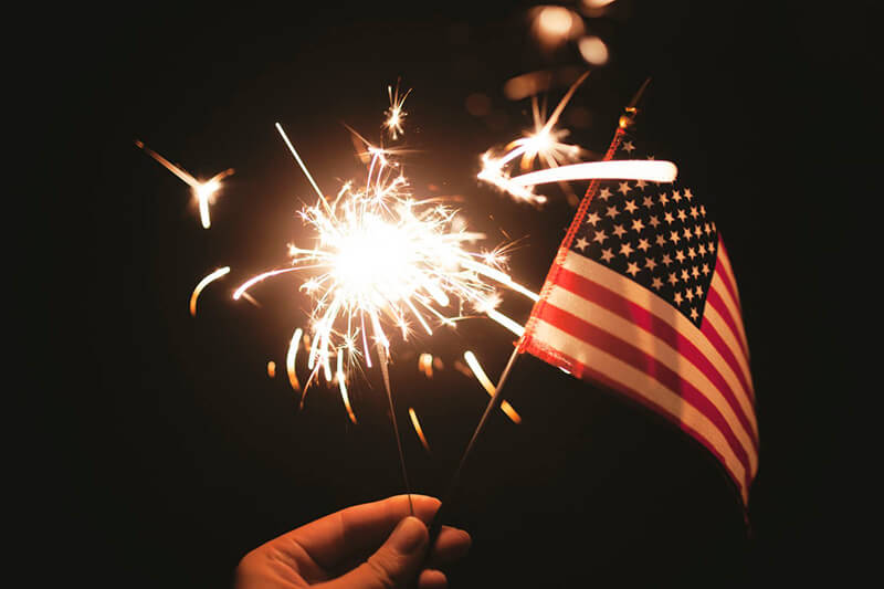 Hand holding a sparkler and small American flag