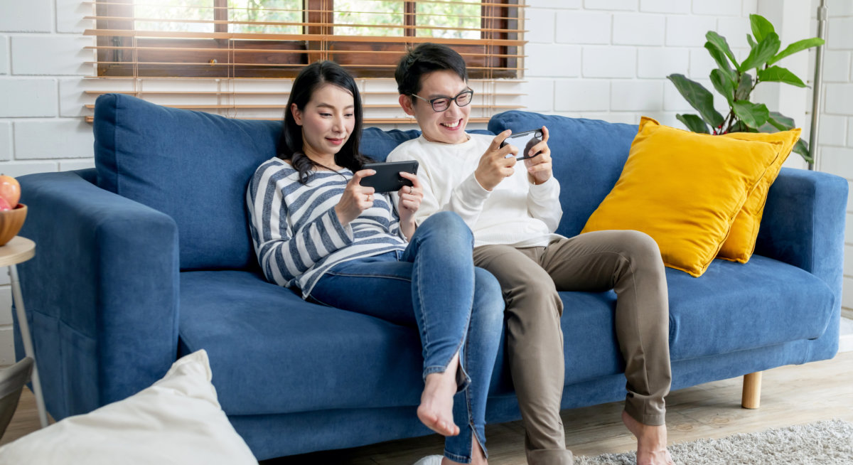 Couple seated on sofa in there apartment using their smartphones