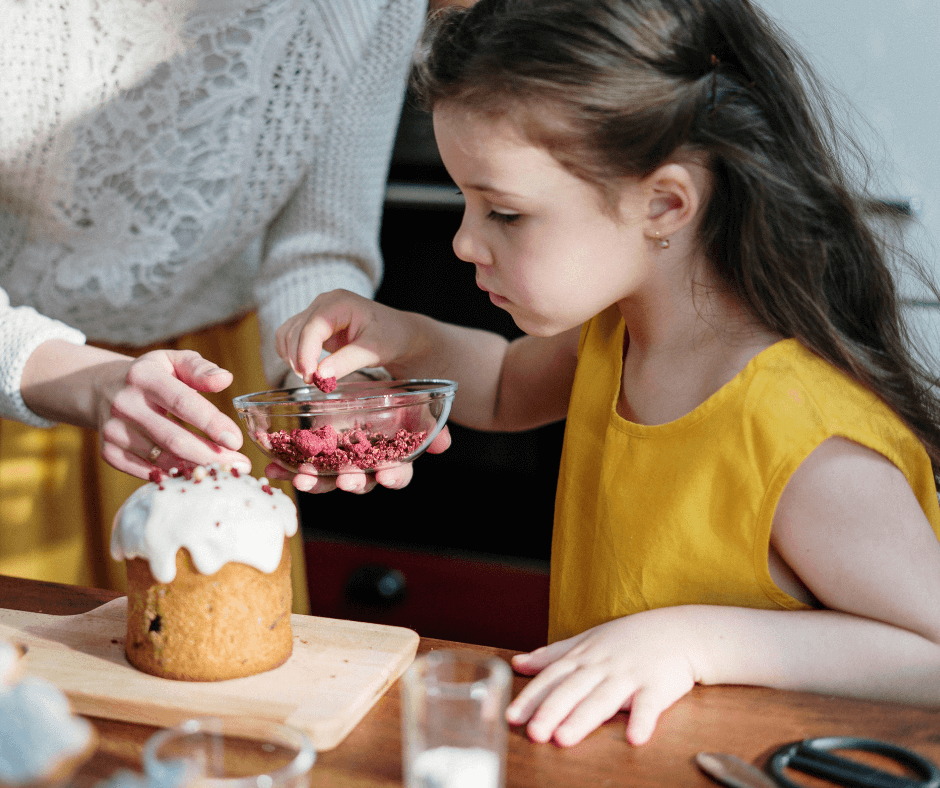 Young girl sprinkling toppings on a desert with her mother