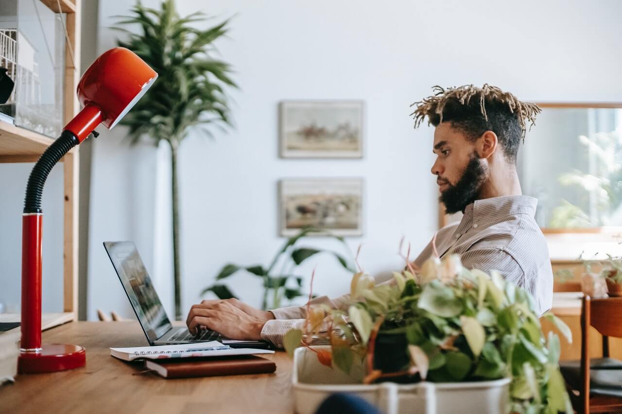 Man sitting at a table working on his computer. Image credit: Zen Chung