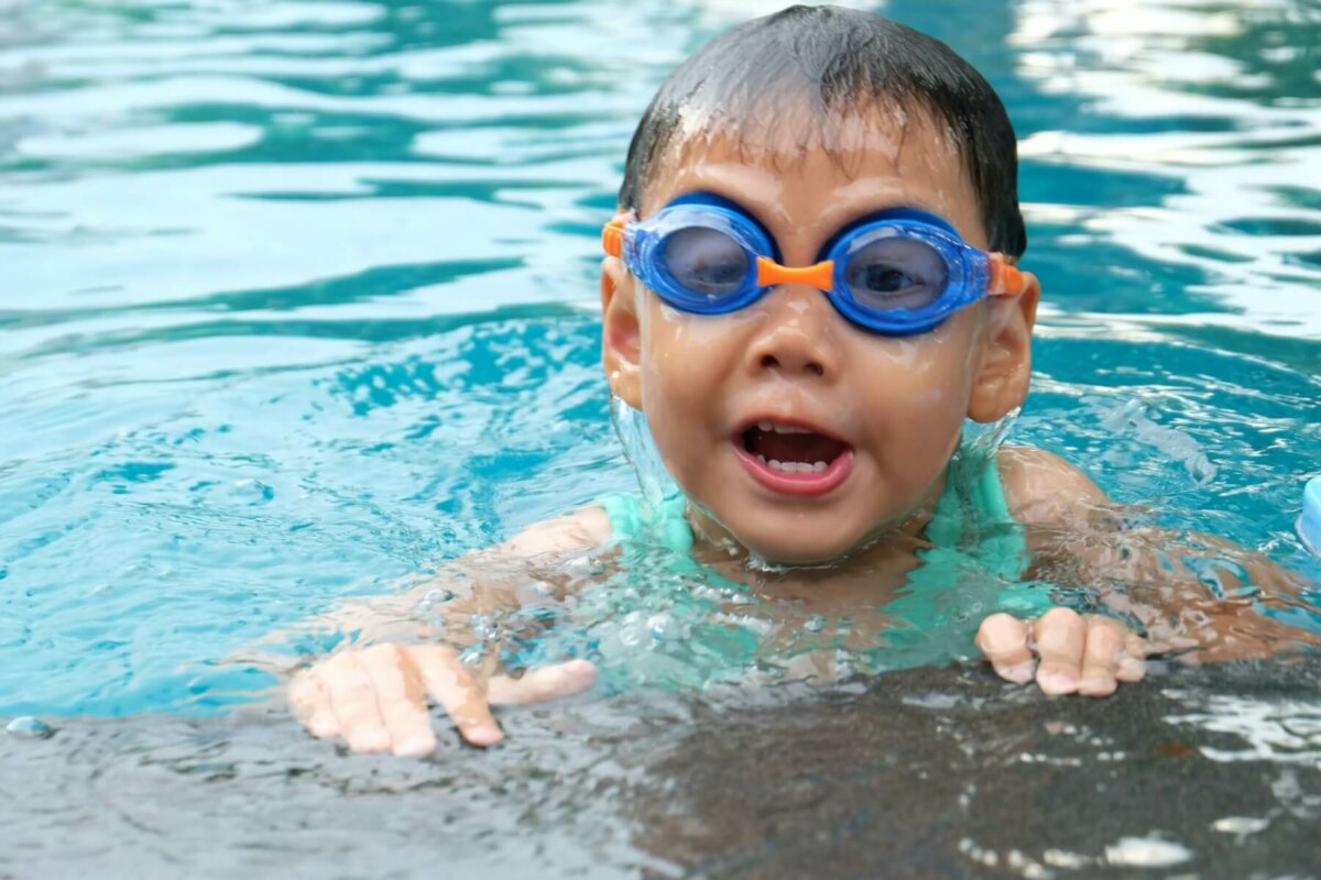 Young boy wearing swimming goggles in a pool. Image credit Porapak Apichodilok