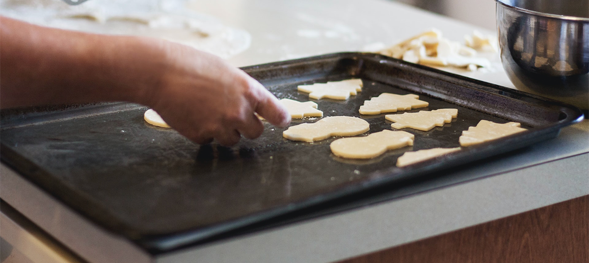 Woman placing cut out cookies on a baking sheet