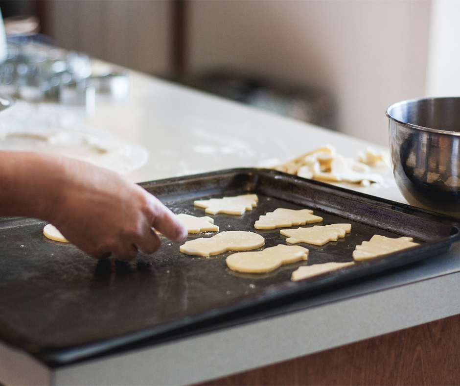 Woman placing cut out cookies on a baking sheet