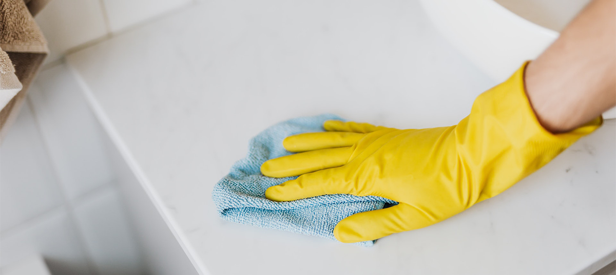 Person using a microfiber cloth to wipe a countertop. Image credit: Karolina Grabowska.