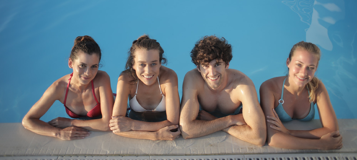 Two young men and two young women relaxing in an in ground pool