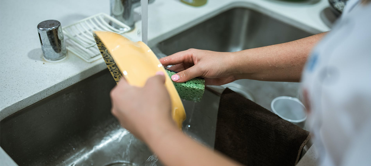 Woman washing a bowl with a sponge. Image credit RDNE Stock Project